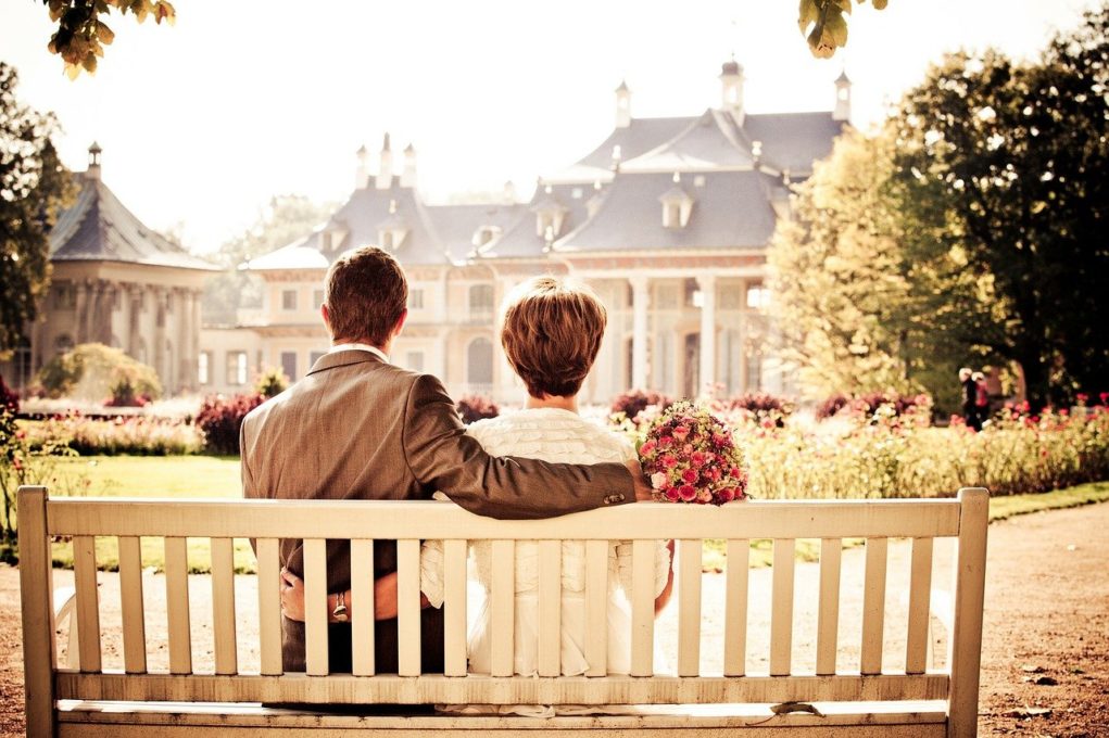 זוג יושבים יחד על ספסל בצבע לבן